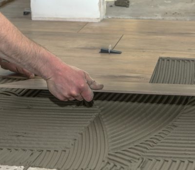 A tiler embarrassed tiles in a freshly filled tile adhesive bed.