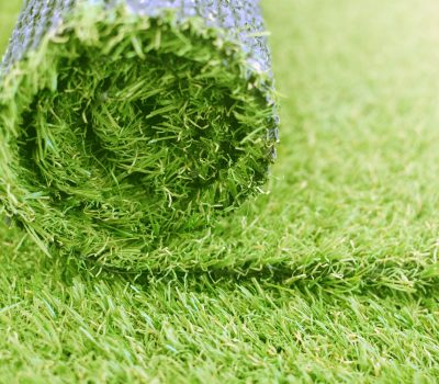 Artificial turf roll. Synthetic grass lawn laying background.